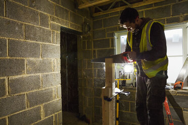 A builder on a home build site using a saw on a block of wood. - MINF07080