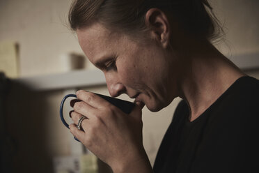 Eine Frau hält sich eine frisch gebrühte Tasse Kaffee an die Nase. - MINF07095