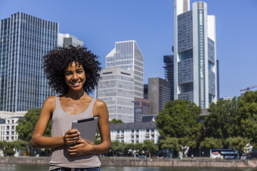 Germany, Frankfurt, portrait of smiling young woman with digital tablet in the city - TCF05569