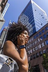 Deutschland, Frankfurt, Porträt einer jungen Frau mit Smartwatch am Telefon vor einem Wolkenkratzer - TCF05582