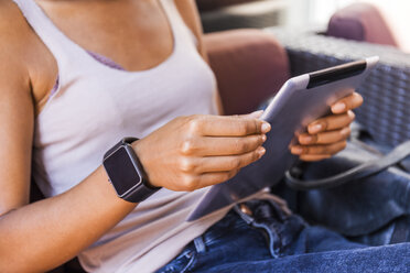 Junge Frau mit Smartwatch sitzt in einem Straßencafé und benutzt ein digitales Tablet, Nahaufnahme - TCF05589