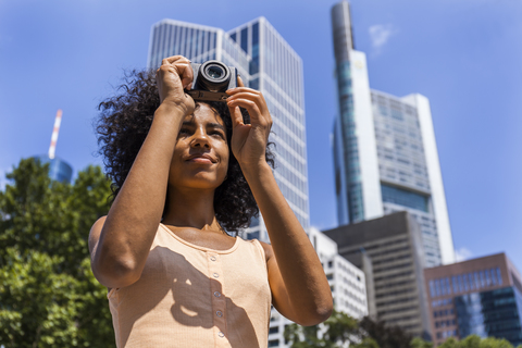 Deutschland, Frankfurt, Porträt einer jungen Frau beim Fotografieren in der Stadt, lizenzfreies Stockfoto