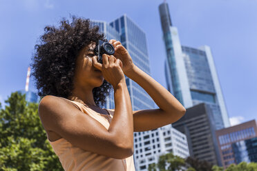 Deutschland, Frankfurt, junge Frau mit lockigem Haar beim Fotografieren in der Stadt - TCF05620