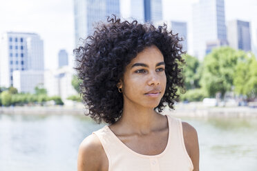 Germany, Frankfurt, portrait of young woman with curly hair in front of Main River - TCF05627