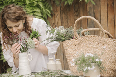 A woman preparing a mixture of herbs for cooking, stripping the leaves off for chopping. - MINF07175