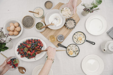 Draufsicht auf einen Tisch mit Speisen in Schalen: Frühstück, Beeren und Joghurt, Eier und Brot. - MINF07184