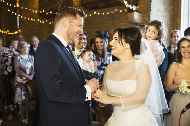Braut und Bräutigam bei ihrer Trauung, Seite an Seite vor den Hochzeitsgästen stehend. - MINF07194