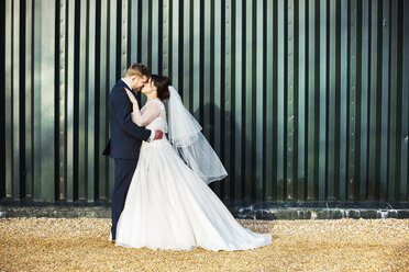 A bride and bridegroom on their wedding day, kissing each other. - MINF07197