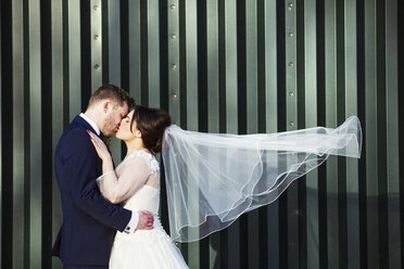 A bride and bridegroom on their wedding day, kissing each other. - MINF07198