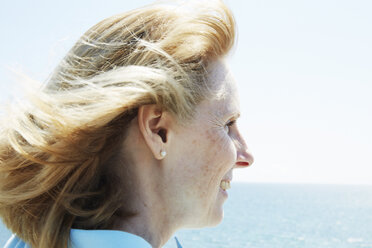 Profil einer blonden reifen Frau, die am Meer steht. - MINF07214