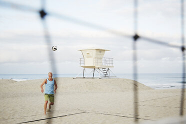 Älterer Mann steht am Strand und spielt Beachvolleyball. - MINF07215