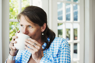 Eine Frau trinkt eine Tasse Kaffee. - MINF07255
