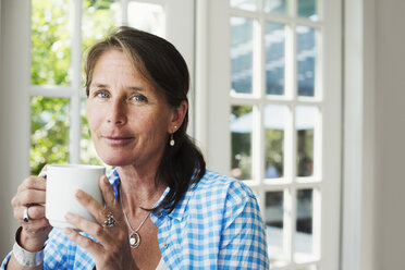 Eine Frau trinkt eine Tasse Tee oder Kaffee. - MINF07256