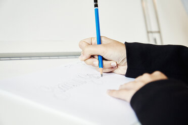 A woman working on a graphic on a drawing board, outlining letters with a pencil. - MINF07316