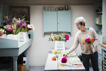 A florist creating a hand tied bunch of fresh flowers. - MINF07342