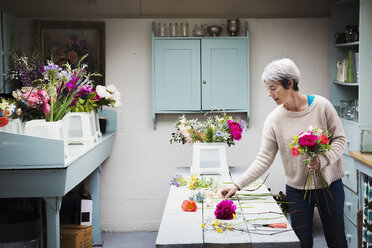 Ein Florist, der einen handgebundenen Strauß frischer Blumen herstellt. - MINF07342