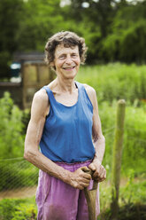 Eine Frau hält eine Schaufel auf einem Bauernhof. - MINF07364