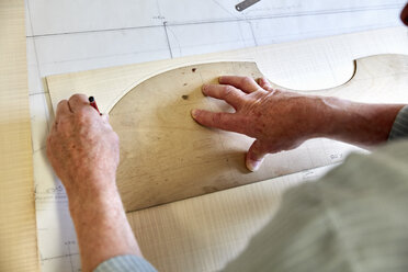 Die Werkstatt eines Geigenbauers: Ein geschickter Handwerker zeichnet den Umriss eines Holzbodens für eine Geige. - MINF07386