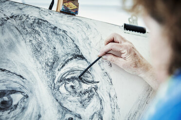 An artist working at her easel, drawing with charcoal on paper - MINF07411