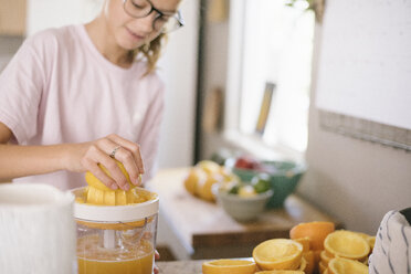 Eine Familie bereitet das Frühstück in einer Küche vor, ein Mädchen presst Orangen aus. - MINF07420