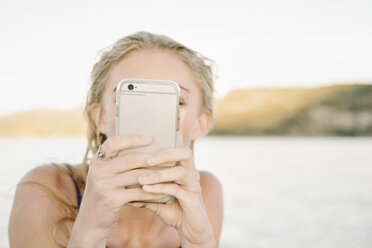 Blonde Frau, die ein Foto mit einem Mobiltelefon macht. - MINF07446