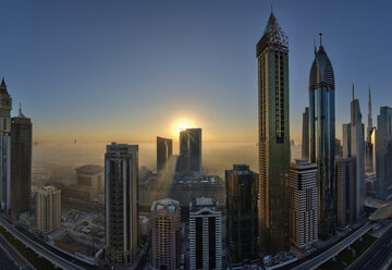 Stadtbild mit beleuchteten Wolkenkratzern in Dubai, Vereinigte Arabische Emirate, in der Abenddämmerung. - MINF07544