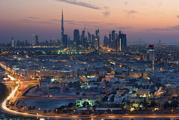 Stadtbild von Dubai, Vereinigte Arabische Emirate, in der Abenddämmerung, mit einer Autobahn im Vordergrund und Wolkenkratzern in der Ferne. - MINF07550