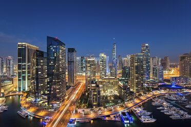 Stadtbild von Dubai, Vereinigte Arabische Emirate, in der Abenddämmerung, mit beleuchteten Wolkenkratzern und dem Yachthafen im Vordergrund. - MINF07558