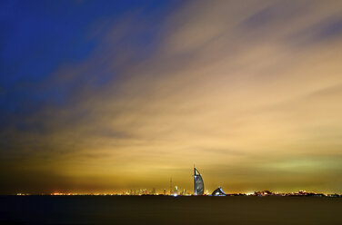 Stadtbild von Dubai, Vereinigte Arabische Emirate, in der Abenddämmerung mit beleuchtetem Burj Al Arab-Wolkenkratzer in der Ferne. - MINF07567