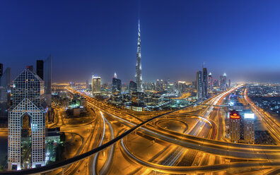 Stadtbild von Dubai, Vereinigte Arabische Emirate, in der Abenddämmerung, mit dem Burj Khalifa-Wolkenkratzer und beleuchteten Autobahnen im Vordergrund. - MINF07578