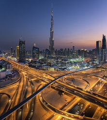 Stadtbild von Dubai, Vereinigte Arabische Emirate, in der Abenddämmerung, mit dem Burj Khalifa-Wolkenkratzer und beleuchteten Autobahnen im Vordergrund. - MINF07585