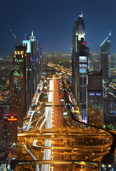 Stadtbild mit Wolkenkratzern und beleuchteter Straße in Dubai, Vereinigte Arabische Emirate, in der Abenddämmerung. - MINF07591