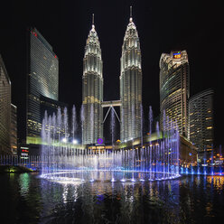 Beleuchtete Petronas-Türme in Kuala Lumpur, Malaysia, bei Nacht, mit einem Springbrunnen im Vordergrund. - MINF07596