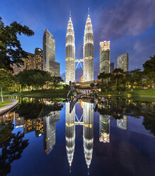 Beleuchtetes Gebäude der Petronas Towers in Kuala Lumpur, Malaysia, in der Abenddämmerung, Spiegelung im See. - MINF07598