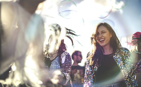 Junge Frauen auf einem Sommer-Musikfestival, die tanzen und Paillettenjacken tragen., lizenzfreies Stockfoto