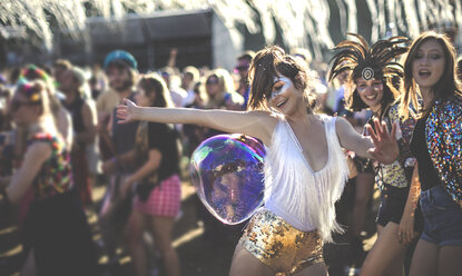 Junge Frau auf einem Sommermusikfestival, die goldene, mit Pailletten besetzte Hotpants trägt und in der Menge tanzt. - MINF07630