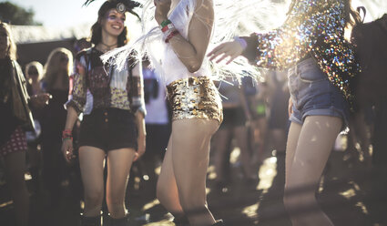 Junge Frau auf einem Sommermusikfestival, die goldene, mit Pailletten besetzte Hotpants trägt und in der Menge tanzt. - MINF07632