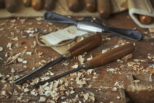 Nahaufnahme von Schnitzwerkzeugen, Meißeln und Holzspänen auf einer Werkbank in der Werkstatt eines Schnitzers. - MINF07648