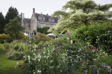 Außenansicht eines Landhauses aus dem 17. Jahrhundert mit Blick auf einen Garten mit Blumenbeeten, Sträuchern und Bäumen. - MINF07663