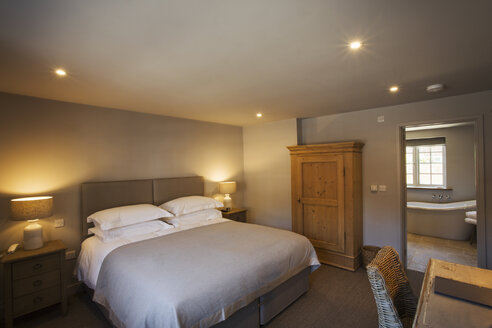 A cosy bedroom decorated in neutral colours, with a double bed and bedside lights on. Hospitality. - MINF07668