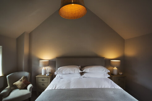 A cosy bedroom decorated in neutral colours, with a double bed and bedside lights on. Hospitality. - MINF07669