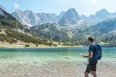 Austria, Tyrol, Man hiking at Seebensee Lake, looking at map - DIGF04738