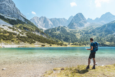 Austria, Tyrol, Man hiking at Seebensee Lake, looking at map - DIGF04739