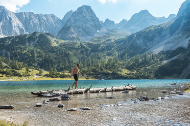 Österreich, Tirol, Junger Mann am Seebensee balanciert auf Baumstamm - DIGF04746