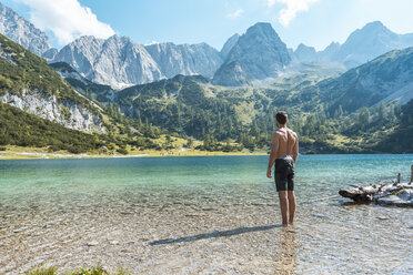 Österreich, Tirol, Junger Mann am Seebensee steht knöcheltief im Wasser - DIGF04749