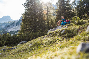 Österreich, Tirol, Wanderer macht eine Pause, sitzt auf einem Felsen - DIGF04754