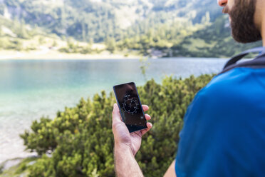 Austria, Tyrol, Hiker using compass app at Lake Seebensee - DIGF04755