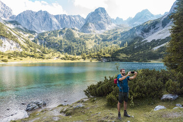 Österreich, Tirol, Wanderer macht Selfies mit seinem Smartphone am Seebensee - DIGF04757