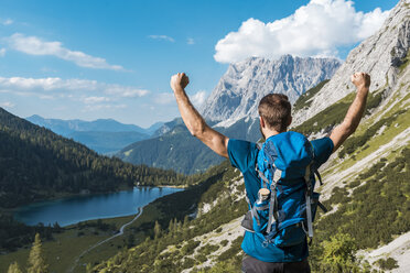 Austria, Tyrol, Hiker with backpack, raising arms, looking at Lake Seebensee - DIGF04760