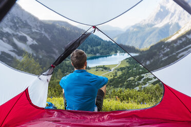 Austria, Tyrol, Hiker relaxing in his tent in the mountains at Lake Seebensee - DIGF04784